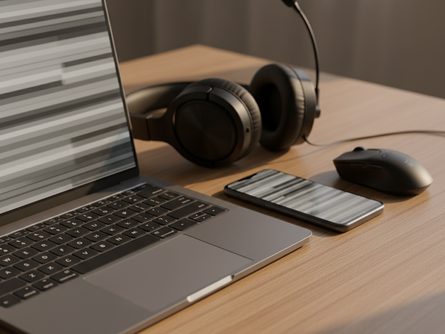 노트북과 스마트폰이 나란히 놓인 책상 위, 헤드셋과 마우스가 함께 있는 모습