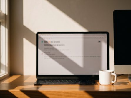 노트북과 스마트폰이 나란히 놓인 책상 위, 컴퓨터 마우스와 이어폰이 함께 배치된 모습